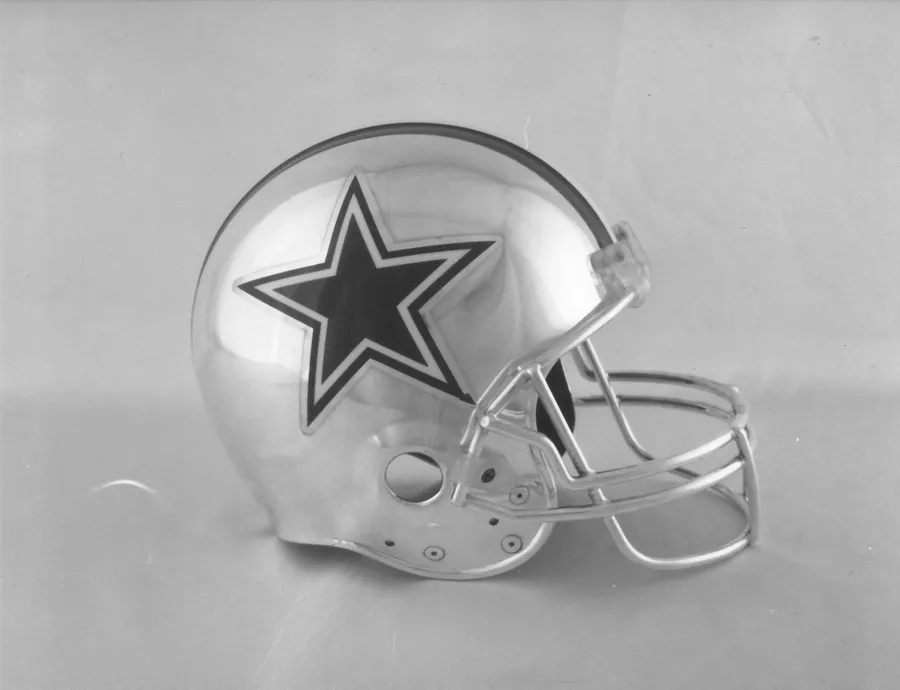 קסדת פוטבול של ה-Dallas Cowboys בגימור כסף מבריק, עם כוכב הקבוצה בצד וסורג פנים מכסף