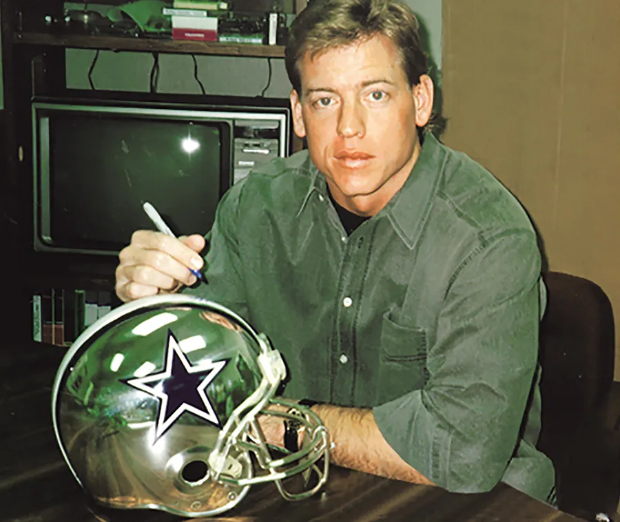 Troy Aikman, קוורטרבק ה-Dallas Cowboys, חותם על קסדת כסף של D’Argenta עם כוכב הקבוצה